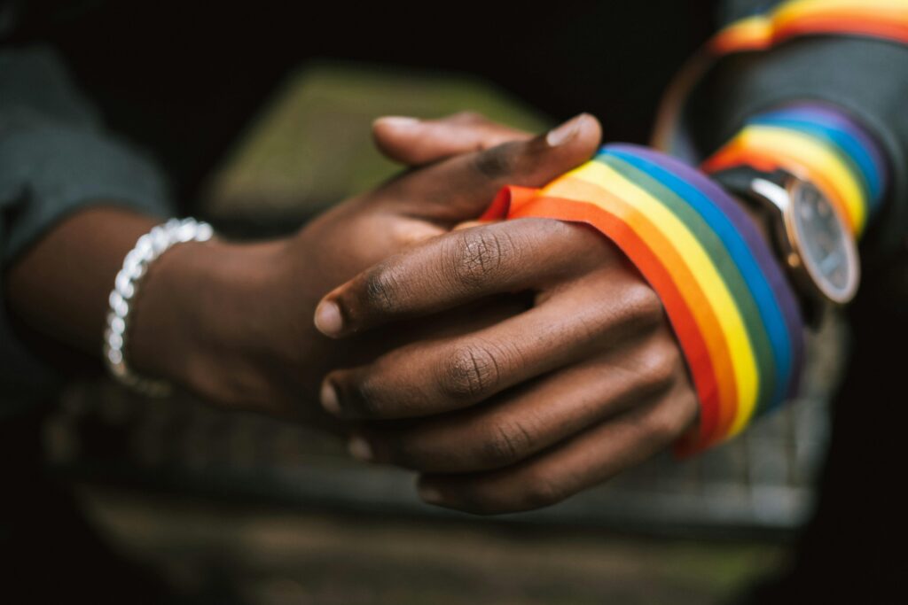 Crop unrecognizable black man wearing LGBT ribbon on arm
