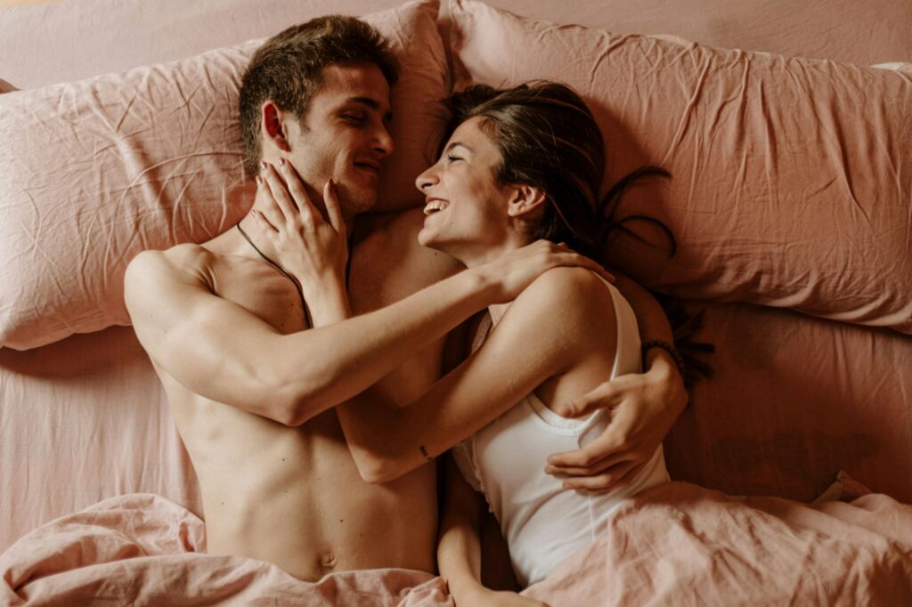 Triamorous couple smiling at each other in bed