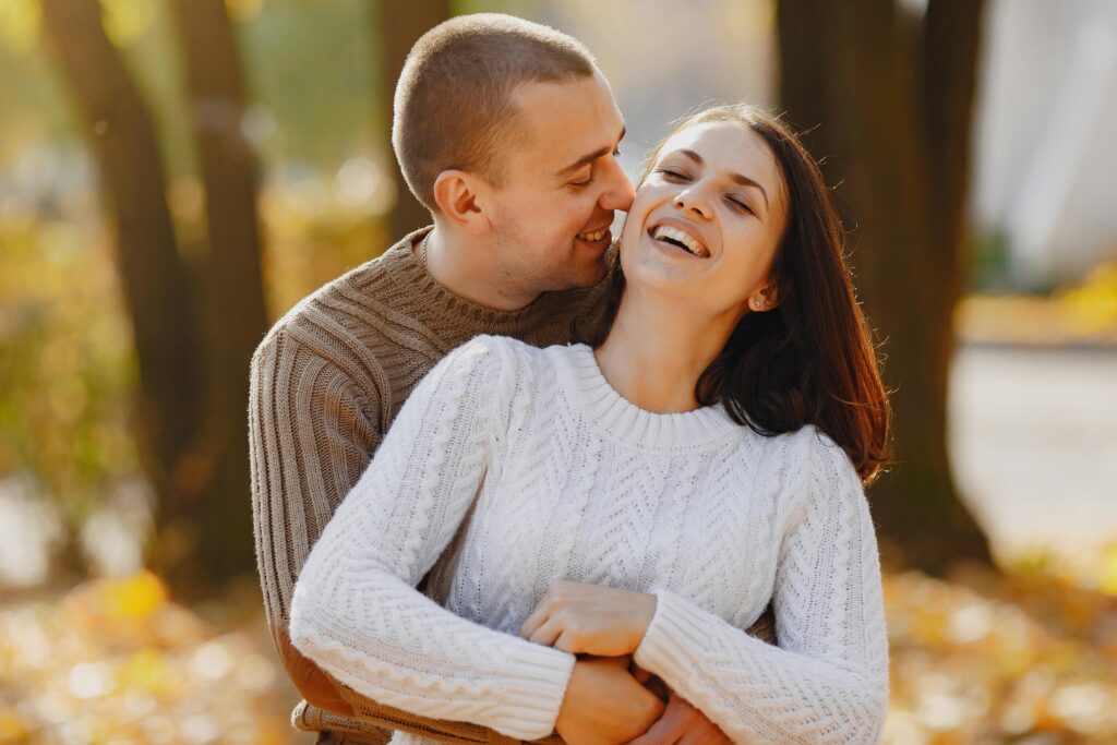 Happy couple in warm clothes hugging on street in autumn day
