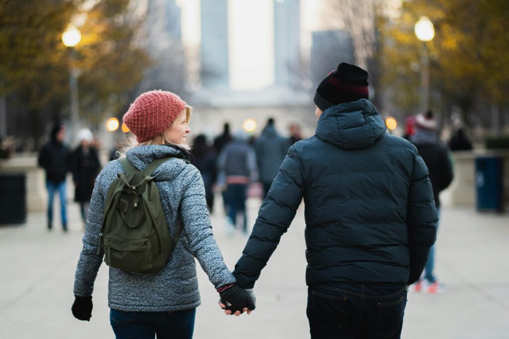 Man and Woman Holding Hands While Walking at Park
