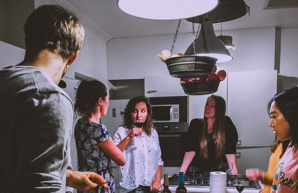 Polyamorous friends hanging out in a kitchen and drinking wine