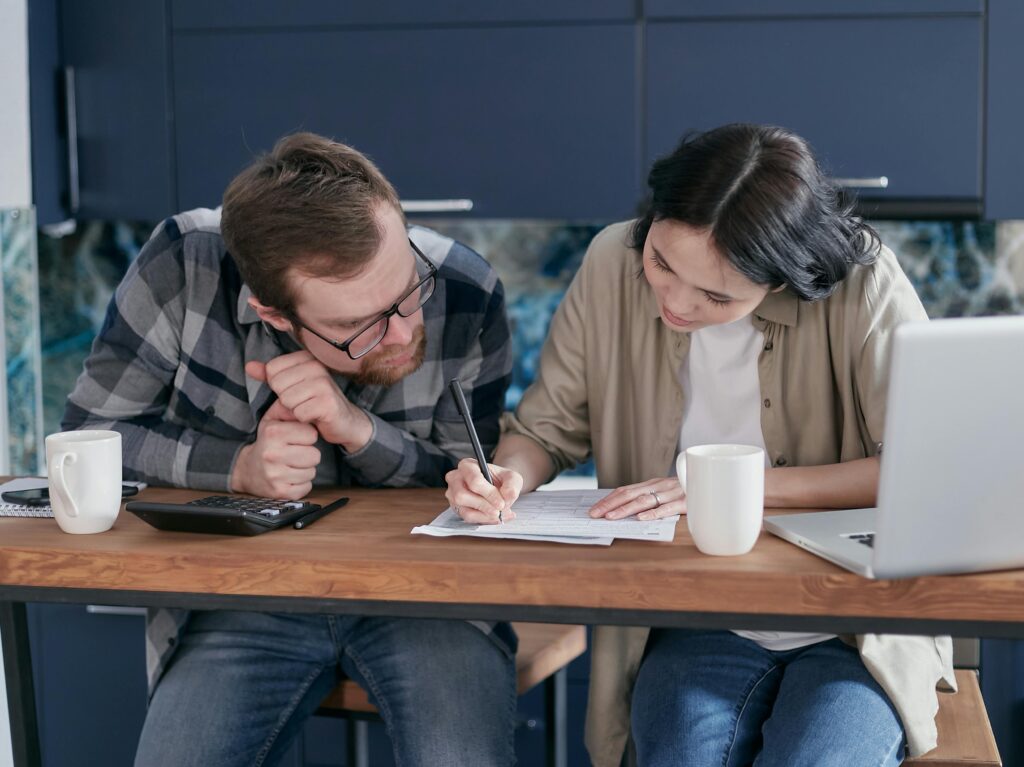 Woman in Brown Shirt Writing on Paper Beside a Man
