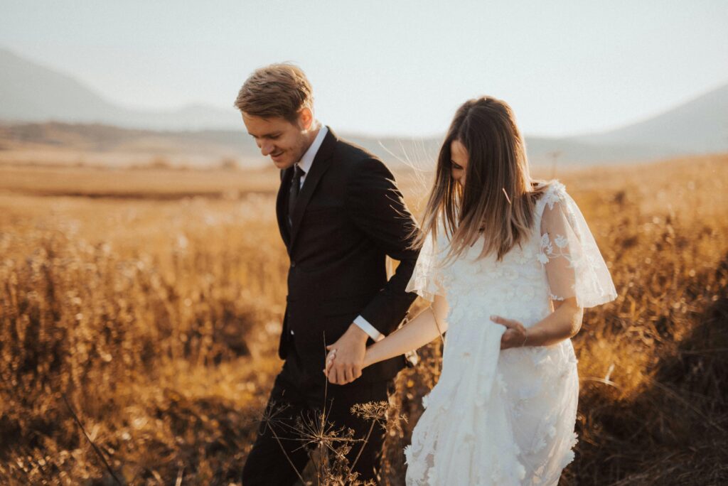 Shallow Focus Photo of Man in Black Formal Suit Holding Woman's Hand in White Dress
