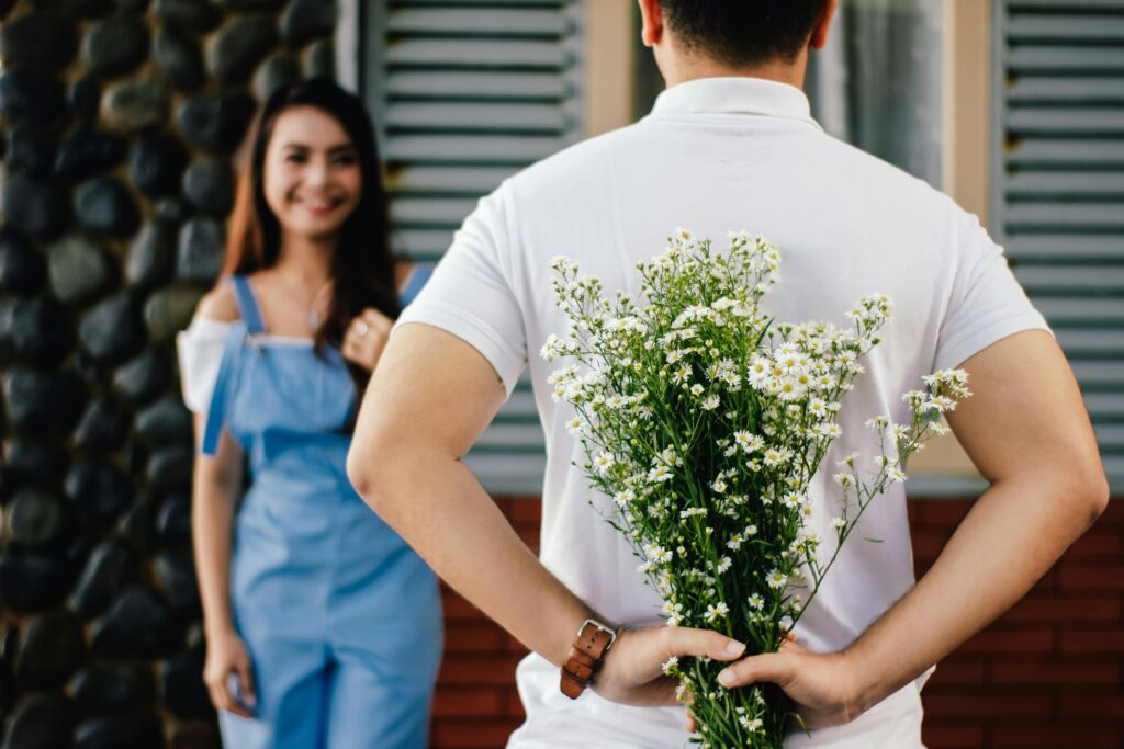 Man Holding Baby's-breath Flower in Front of Woman Standing Near Marble Wall
