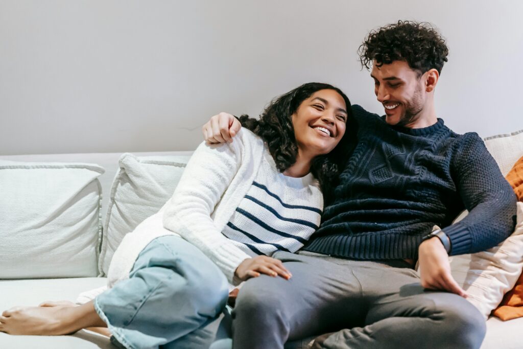 Positive multiethnic couple cuddling on couch
