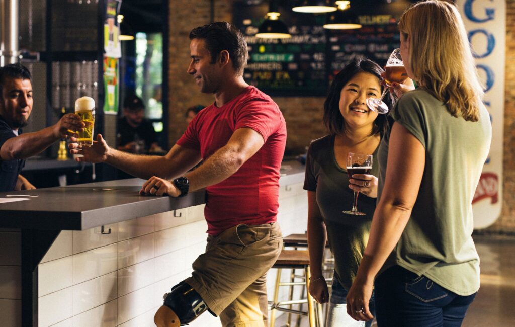 Man Being Served Beer Next to Two Conversing Women
