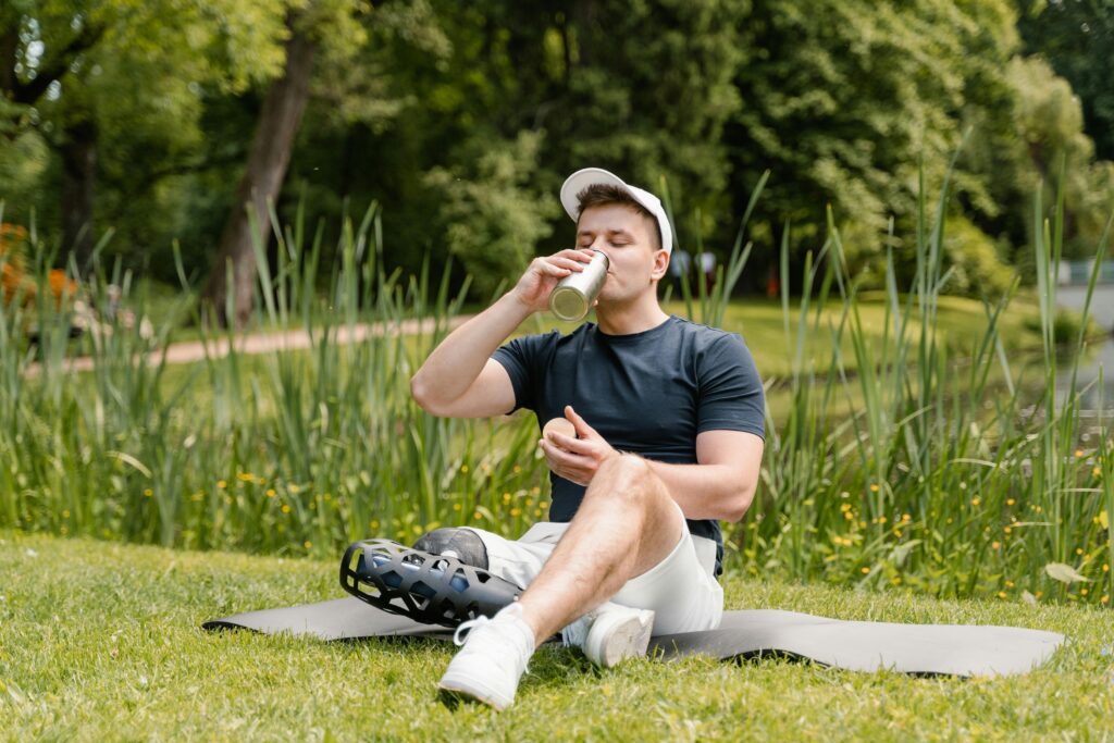 Man Sitting on Yoga Mat While Drinking from a Tumbler