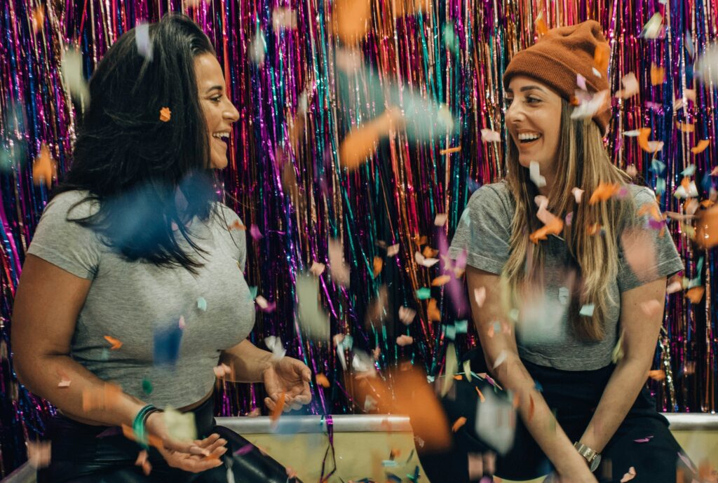 two women kneeling under falling confetti