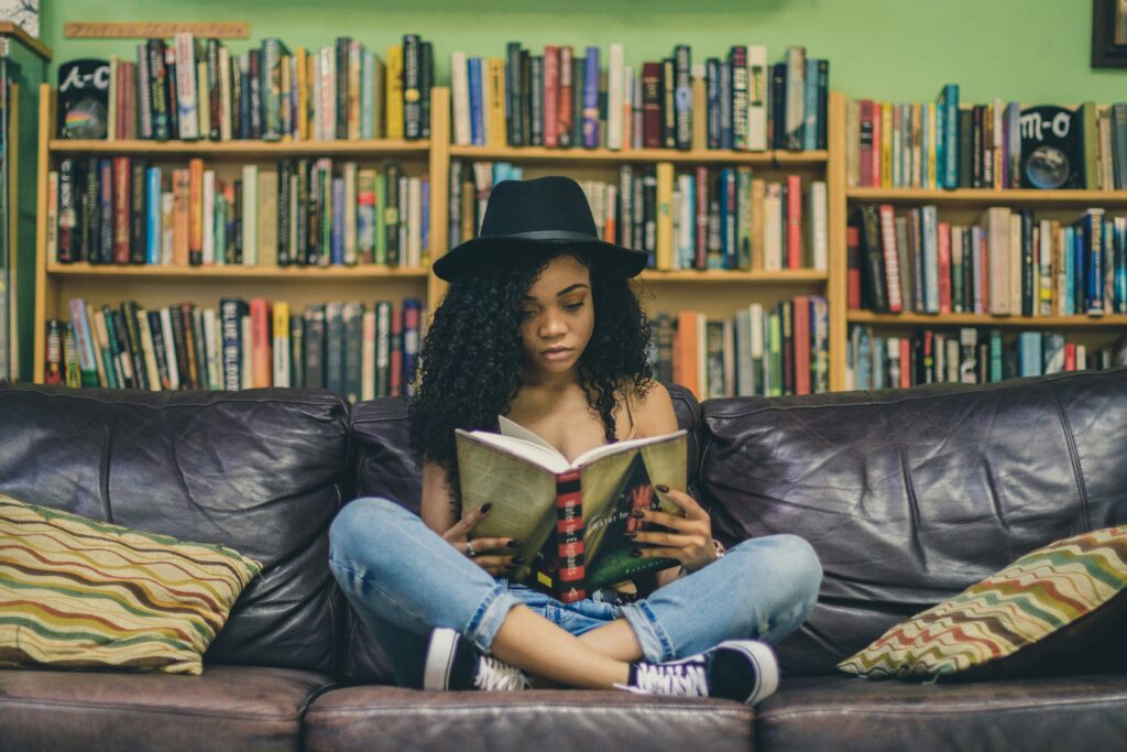 woman reading a book while sitting on black leather 3 seat couch