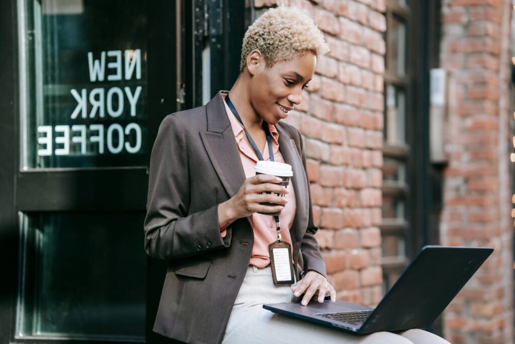 Smiling black entrepreneur watching laptop during coffee break
