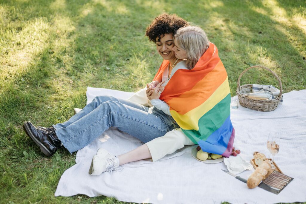 Women Hugging Each Other While Wrap with the Pride Flag
