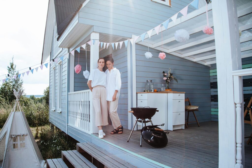 Two Women Standing on the Porch of a House

