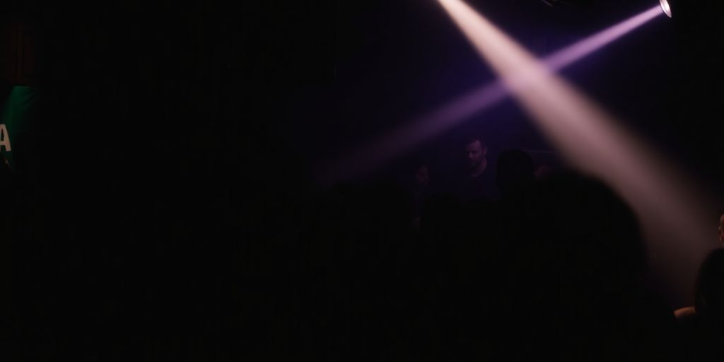Silhouetted figures in a dimly lit club space.